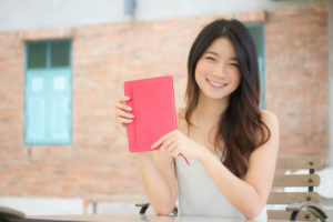 赤い本を携えて微笑む、留学生の女子大生
