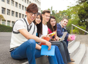 5人の留学生がならんで座って、こちらに向かって微笑んでいる