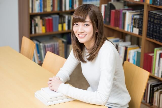 図書館で席に座っている女性が笑顔でカメラ目線