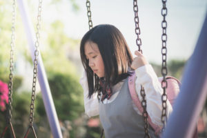 外国人であることを理由に仲間外れにされて、一人ブランコをこぐ女の子