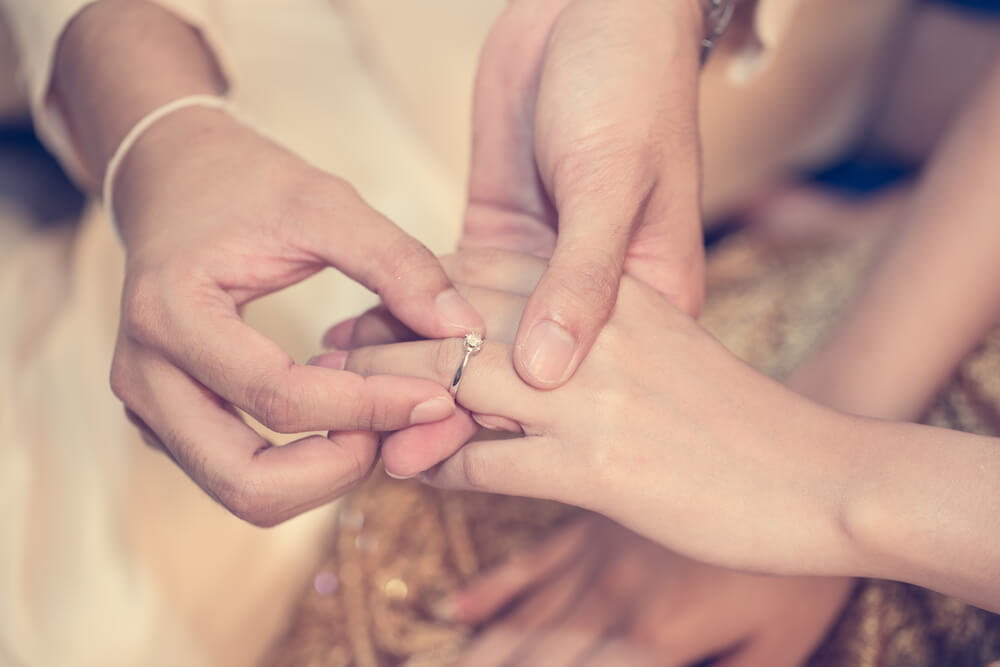 男性が女性の薬指に結婚指輪をはめている