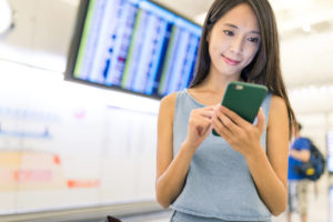 空国でスマホを使い調べ物をしている女性