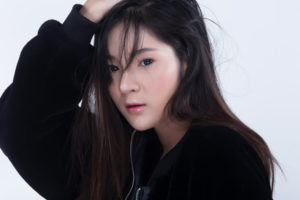 前髪をかきあげてこちらを見つめる若いアジア人女性
