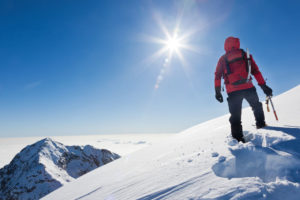 晴れた雪山を登山途中の男性