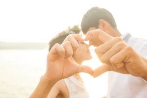 キスをしながらお互いの手でハートを作る新郎新婦