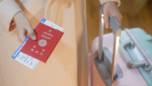 日本のパスポートを差し出す、キャリーバッグを引いている女性