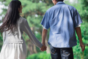 手をつないで歩く若いカップルの後ろ姿