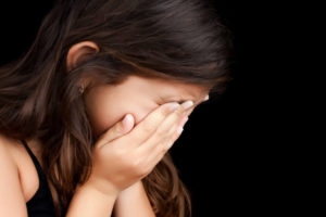 跛行婚によって親と会えなくなった女の子が顔を覆って泣いている