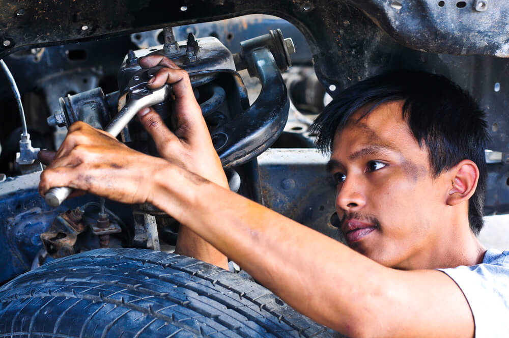 オイルに汚れながら車の整備を進める東南アジアの男性