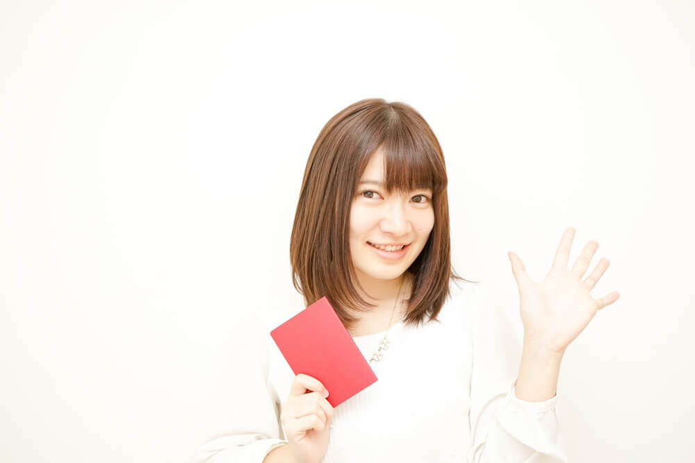 日本のパスポートをもって、こちらに手を振る日本人女性