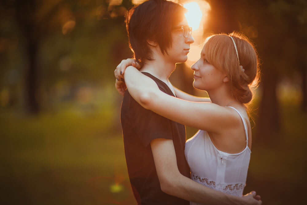 夕日が差し込む森の中で、静かに抱き合う国際結婚カップル