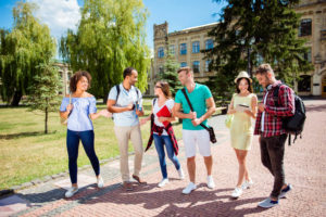 晴れ渡った中、キャンパスを談笑しながら歩くいろいろな国籍の学生たち