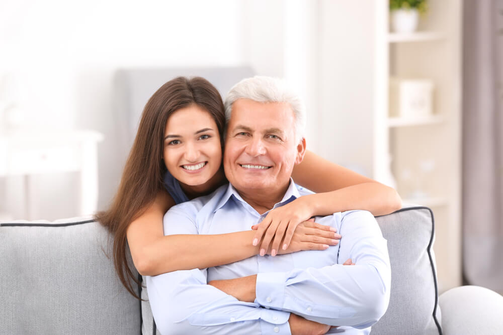 親子ほど年が離れた国際結婚カップル。若い女性が年齢がかなり高い男性に抱きついている