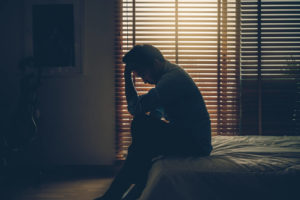 暗い部屋の中で頭を抱える男性