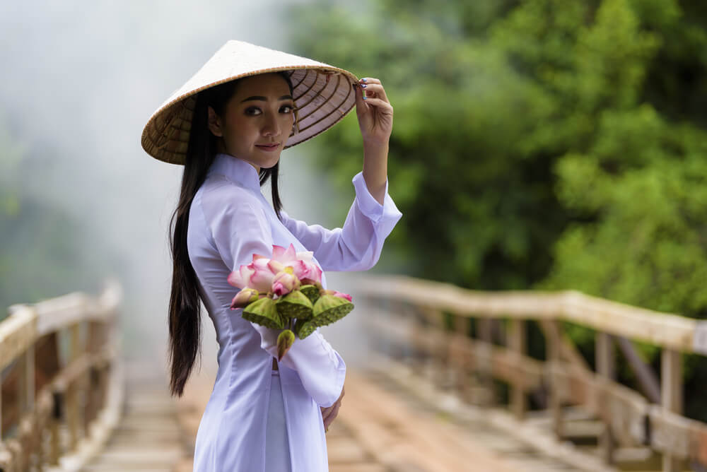 国際結婚を考える、アオザイを着てこちらに花束を渡そうとしている若いベトナム人女性